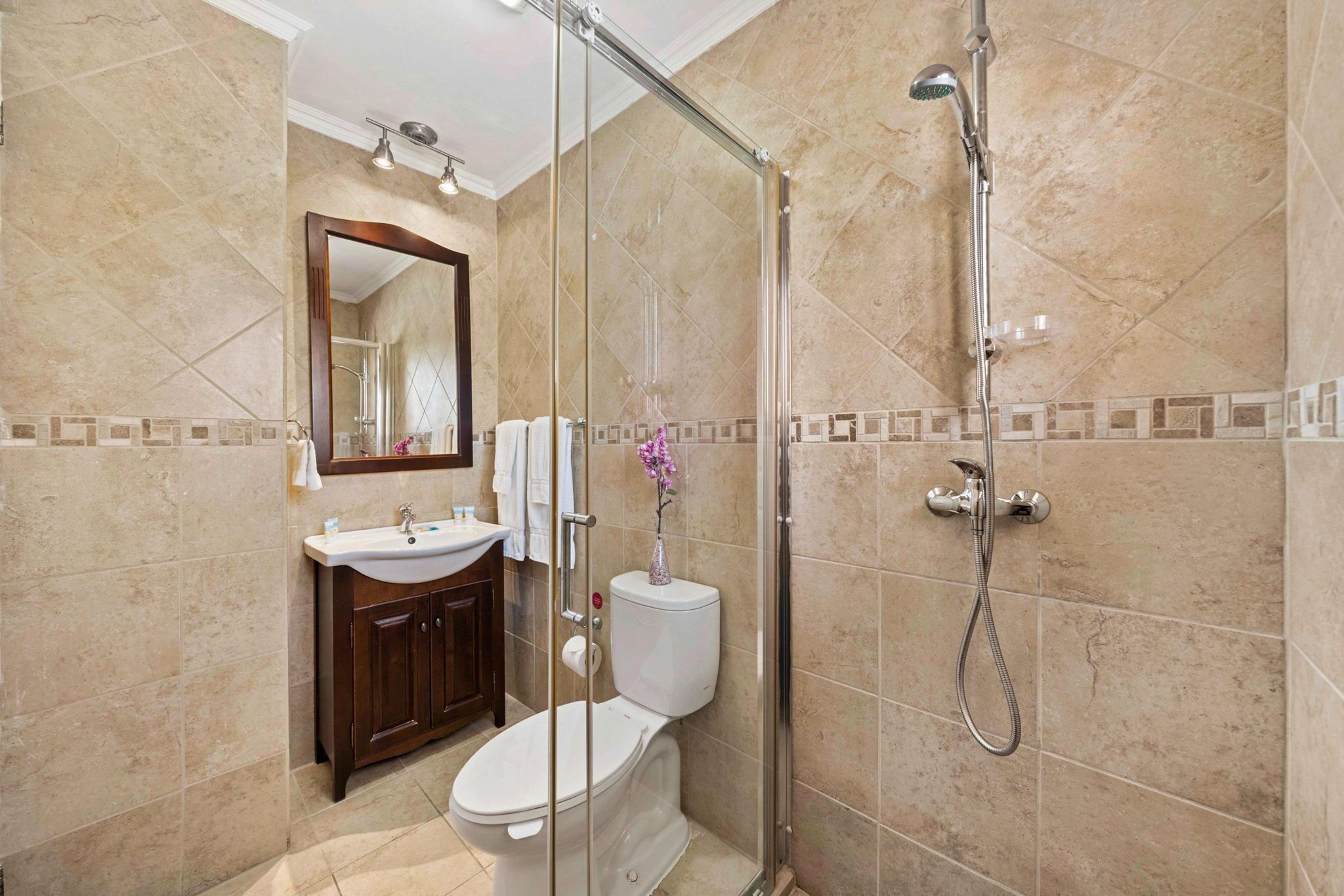 Ein Badezimmer mit einer gläsernen Duschkabine, einem Waschbecken und einer Toilette.