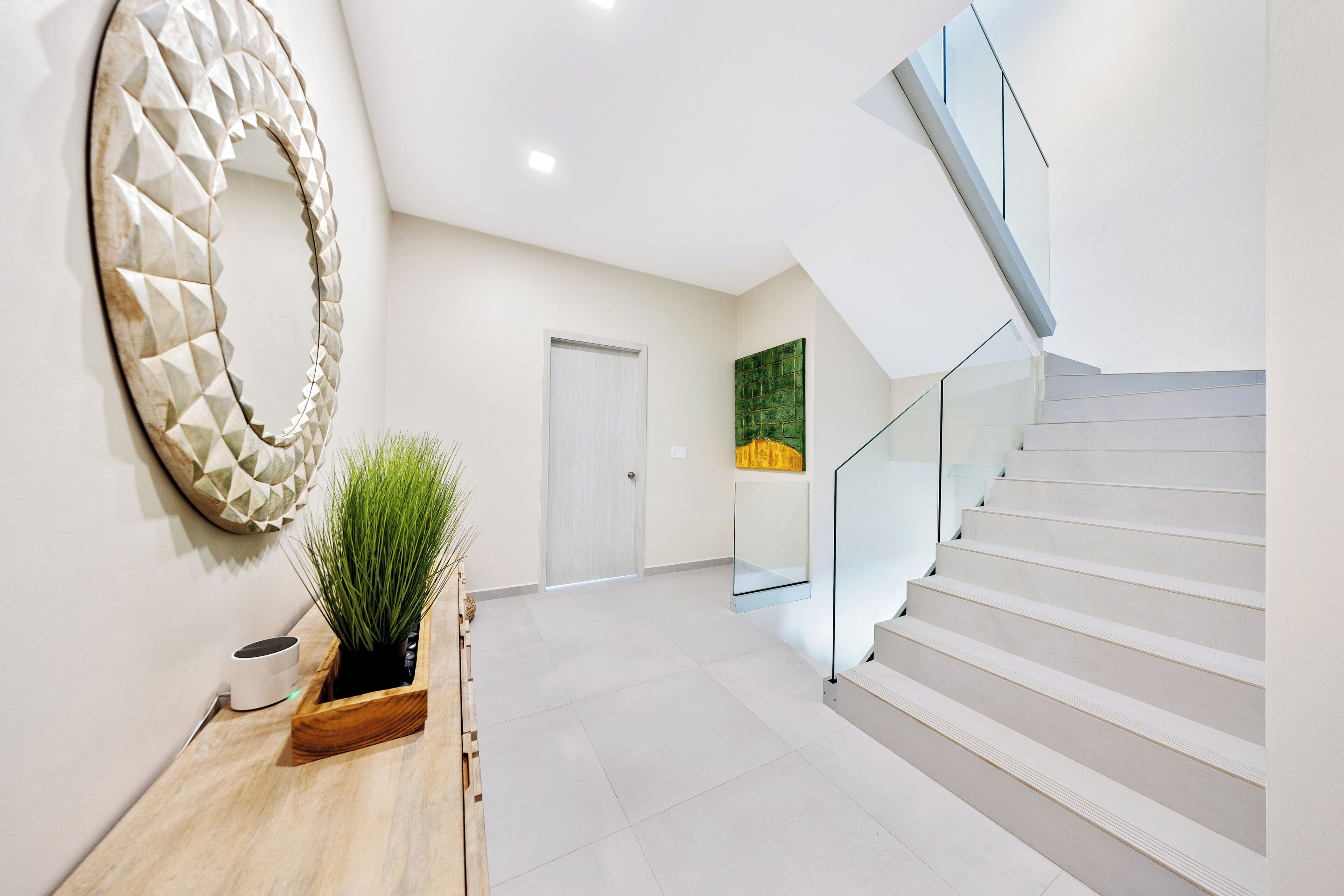 Een modern interieur met een trap, een spiegel aan de muur en een potplant.