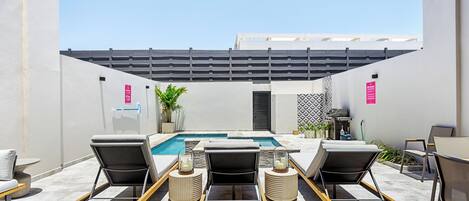 A rooftop pool area with lounge chairs, a pool, and a pergola.