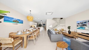 A modern living space with a dining area, sofa, and staircase. - Catalina Residence Apt 3 - L.g. Smith Boulevard 546-j (Noord)