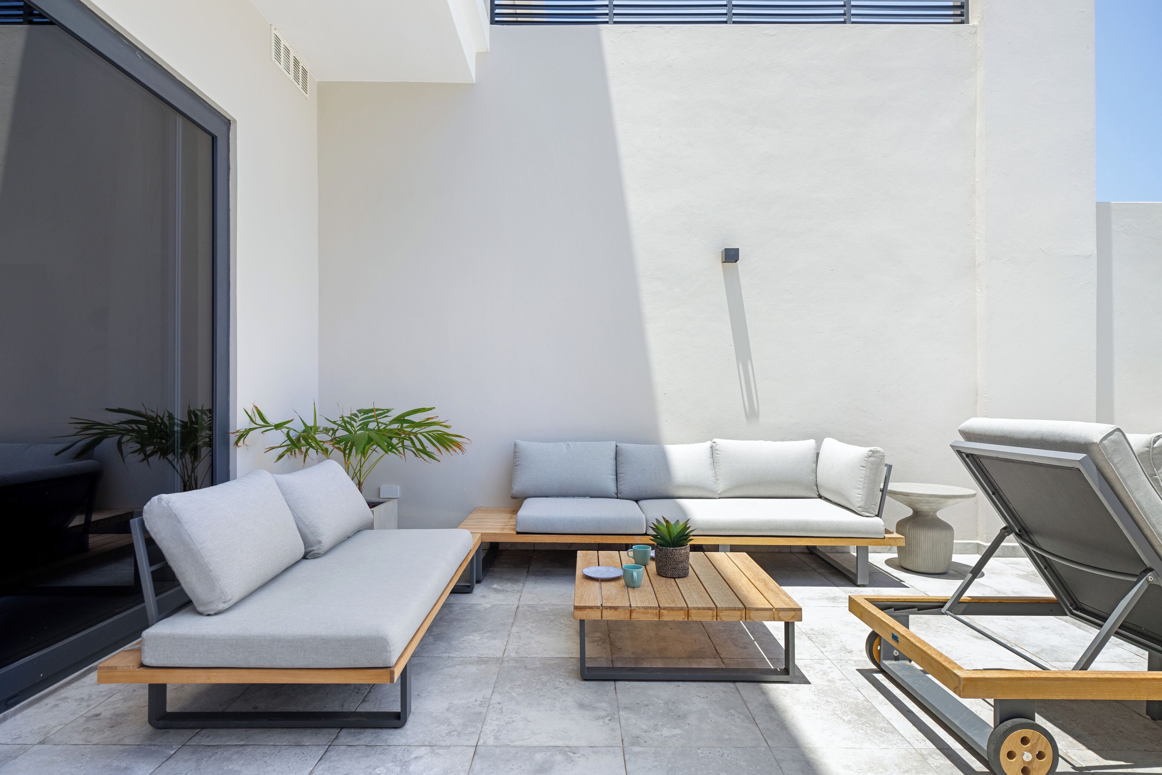 A modern outdoor seating area with a sofa, lounge chairs, and a coffee table.