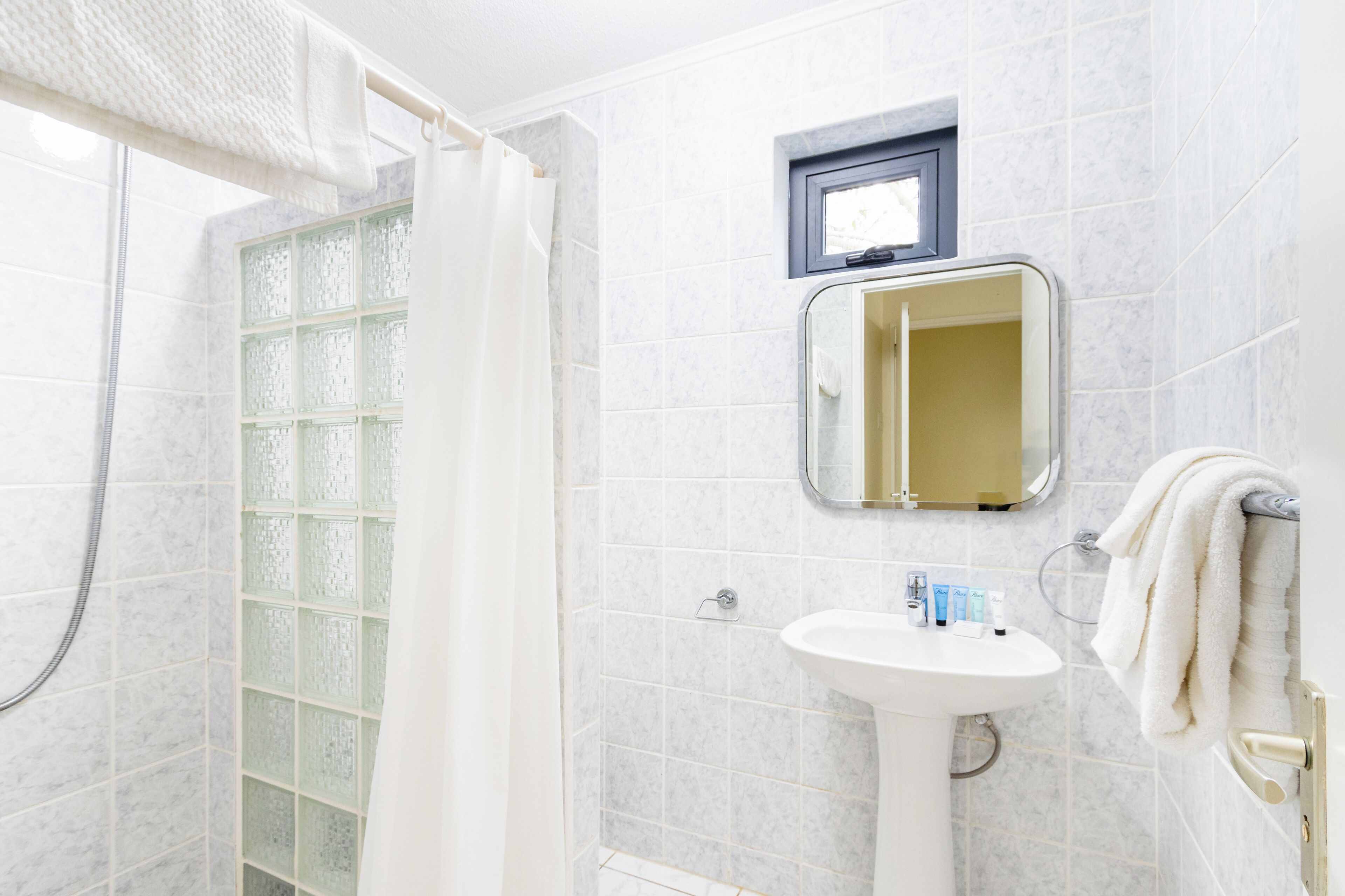 Ein Badezimmer mit Dusche, Waschbecken und Spiegel.