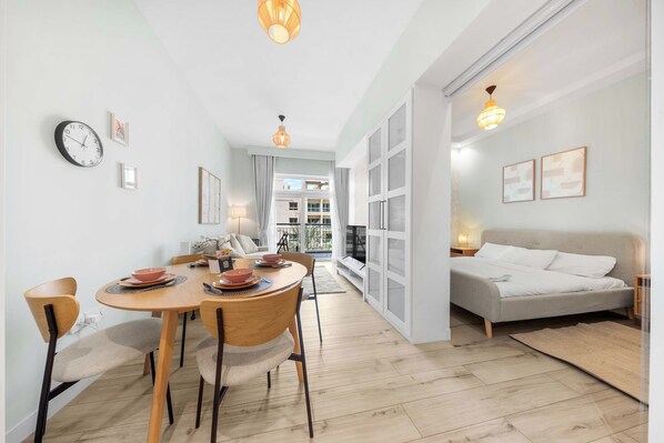 A modern interior with a dining area, a sofa, and a bed.