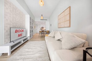 A modern living room with a sofa, a TV, and a dining area.