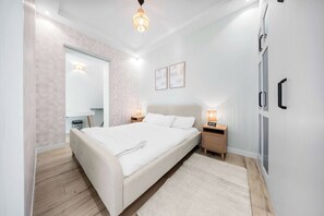 Un dormitorio moderno con una cama grande, mesitas de noche con lámparas, un armario y un espejo.