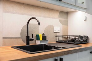 A modern kitchen with a black sink, a faucet, a soap dispenser, and a dish rack.