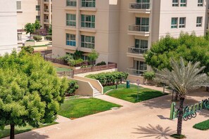 A multi-story residential building with balconies, a bike-sharing station, and a well-maintained garden area.