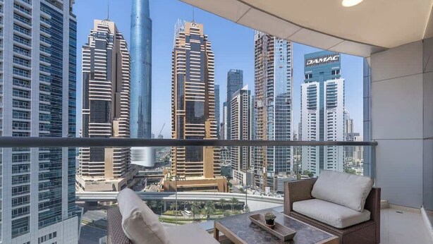 Varanda com mobiliário de vime e vista para edifícios altos.