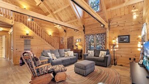 A log cabin interior with a staircase, two sofas, a rocking chair, and a rug. - Remmert`s Log Haven - Tranquil Mountain Getaway (Estes Park)