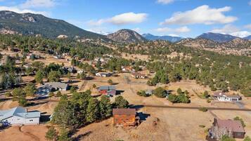 An aerial view of a residential area with houses, roads, and mountains in the background.