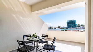 A balcony with a table and chairs, a potted plant, and a view of a construction site. - Andrea 3-Bedroom Apt in Mackenzie W/ Pool (Cyprus - Larnaca)