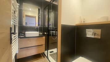 Une salle de bain moderne avec une douche à parois de verre, un lavabo blanc et un meuble-lavabo en bois.