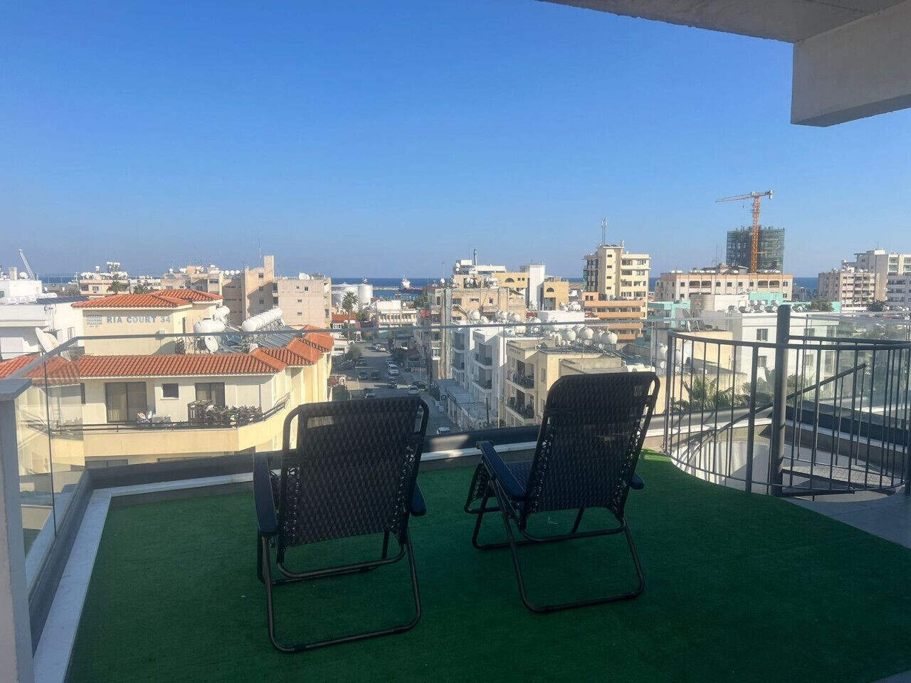 A balcony with two chairs and a view of the city and sea.