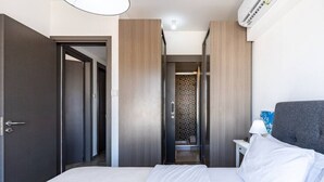A modern hotel room with a large bed, a bedside table with a lamp, and a wardrobe. - Maryam's 2-BR Apt Facing Larnaca Harbor W/ Pool (Cyprus - Larnaca)