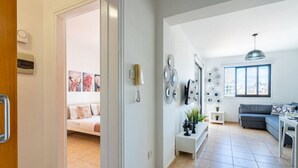 A modern living room with a sofa, a dining area with a table, and a kitchen area with a fridge.