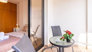 A modern bedroom with a bed, a small table with a potted plant, and a chair.