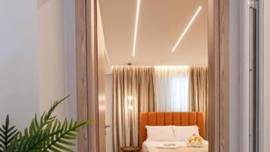 A modern hotel room with a large bed, a bedside table, and a potted plant. - Vila Murati (Ksamil)