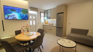 A modern living space with a dining area, kitchen, and a large TV displaying a scenic view. - Vila Murati (Ksamil)
