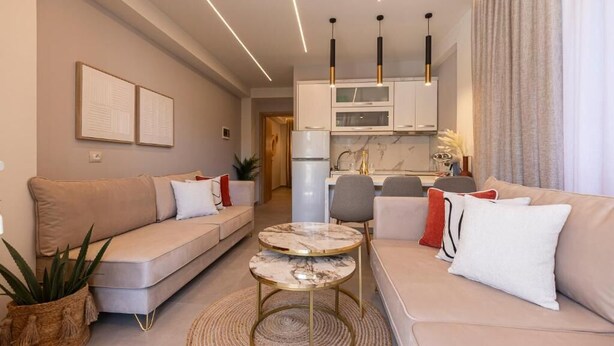 A modern living room with a sofa, a coffee table, and a kitchen in the background. - Vila Murati (Ksamil)
