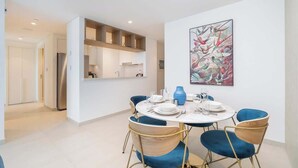 Un comedor moderno con una mesa redonda, sillas azules y un jarrón decorativo.