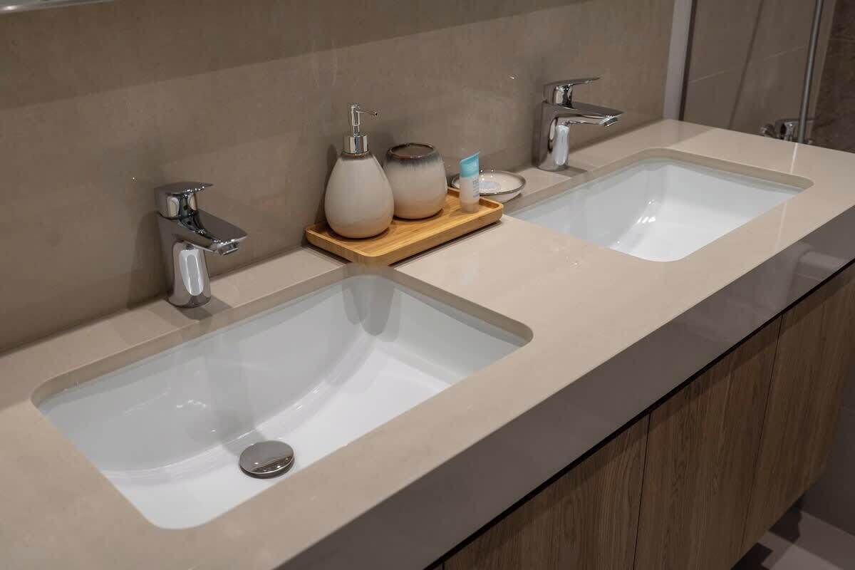 Un baño moderno con dos lavamanos, un tocador y un espejo.