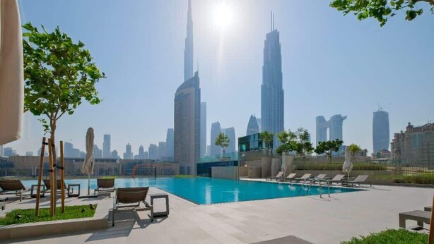 Área de piscina en la azotea con sillones de descanso y vistas al horizonte de la ciudad.