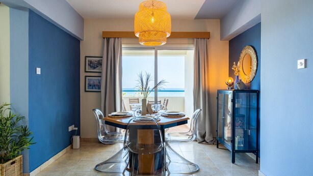 A dining area with a round table, clear chairs, and a hanging light fixture. - Bayview 2-BR Apartment in Larnaca (Cyprus - Larnaca)