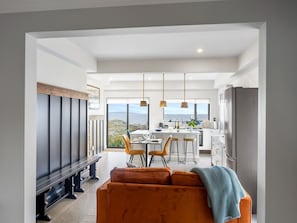 A modern kitchen with a dining area, large windows, and a view of the outdoors.