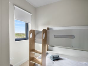 Un lit superposé avec une échelle, une fenêtre donnant sur un beau paysage et un mur blanc.