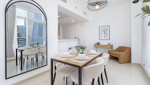 Un comedor moderno con un espejo grande, una mesa para cuatro personas y una zona de estar acogedora.