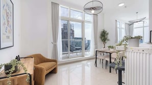Una sala moderna con sofá, mesa de comedor, sillas y ventanas amplias que ofrecen vista a la ciudad.
