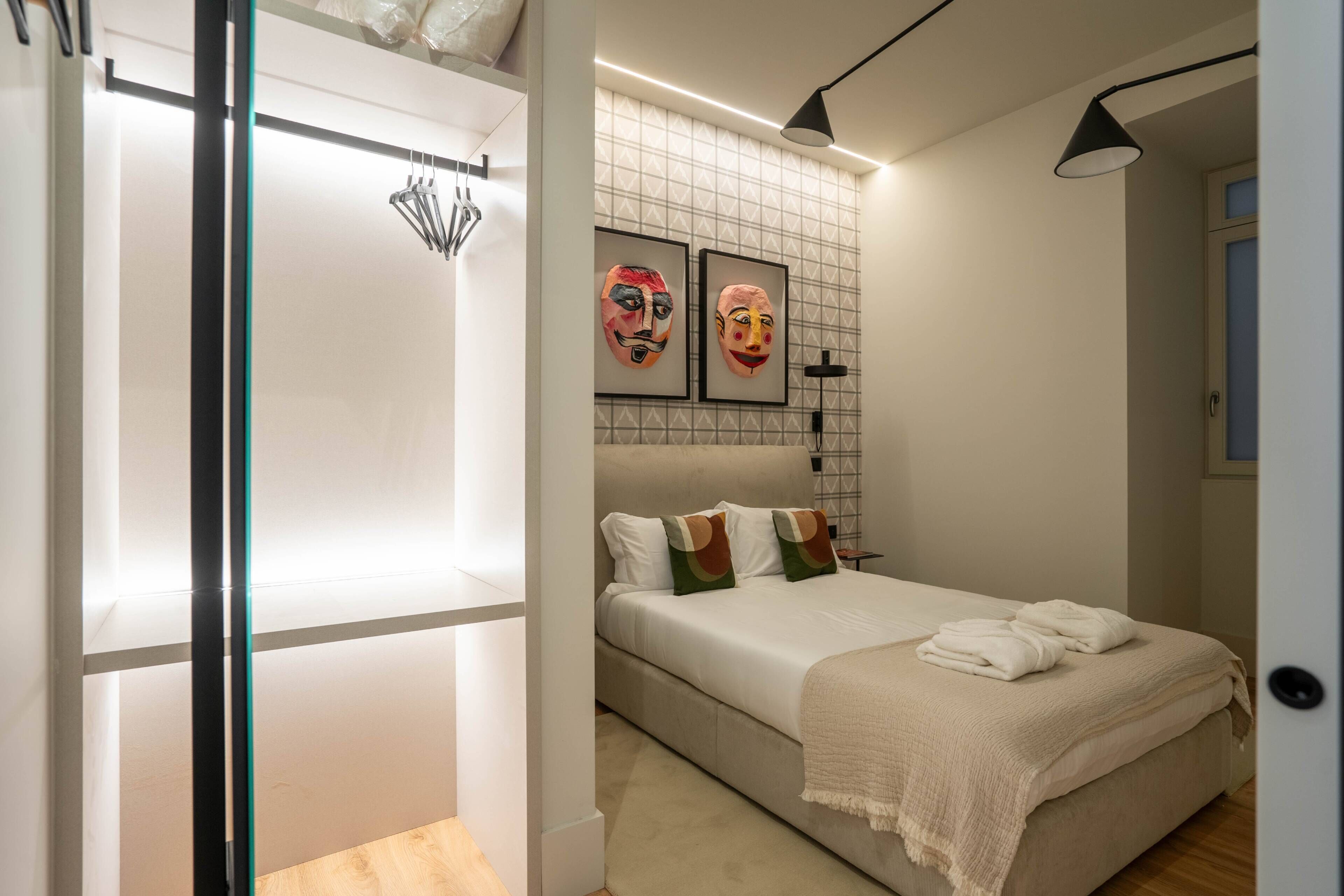 Un dormitorio moderno con una cama, un armario y dos máscaras enmarcadas en la pared.