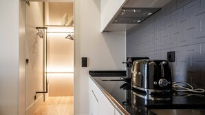 Une cuisine moderne avec un plan de travail noir, des appareils en acier inoxydable et un pare-feu en carreaux.
