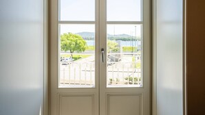 Une porte blanche donnant sur un lac et un arbre.