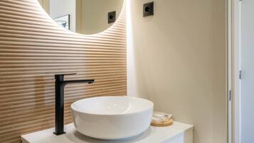 A modern bathroom with a white sink, black faucet, and a wooden slatted wall.