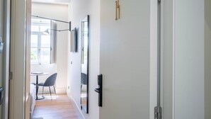 Habitación de hotel moderna con piso de madera, una cama, un escritorio y una silla. Hay una ventana que ofrece vistas al exterior.