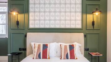 A neatly made bed with two pillows, a bedside table with a book, and two wall-mounted lamps.