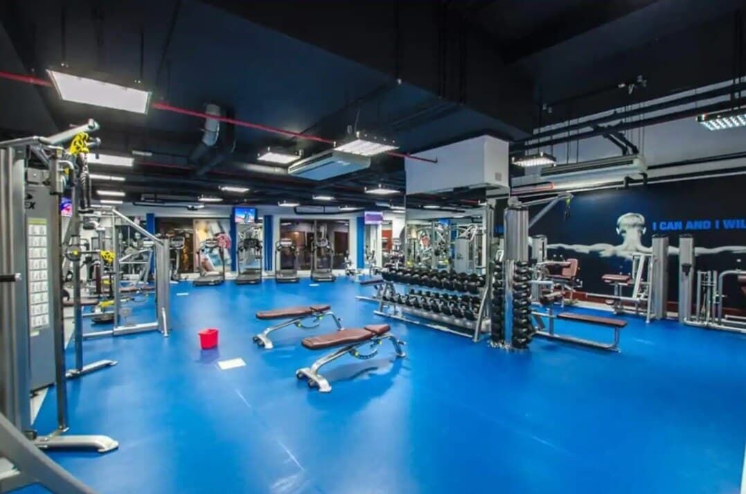 Un gimnasio con diversos equipos de ejercicio, bancos y mancuernas.