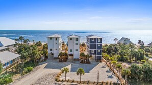 Una proprietà fronte spiaggia con edifici a tre piani, un vialetto sabbioso e vista sull'oceano.