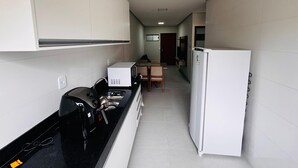 Une cuisine compacte équipée d’une cuisinière, d’un four à micro-ondes et d’un réfrigérateur, qui donne sur un coin repas avec une table et des chaises.