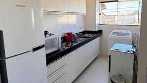 Une cuisine moderne avec des armoires blanches, un réfrigérateur en acier inoxydable, un four à micro-ondes et un lave-vaisselle.