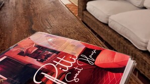 Un magazine posé sur une table en bois dans un salon, avec un canapé et un coussin à pois.