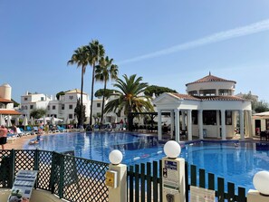 A pool area with lounge chairs and a gazebo.