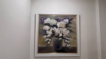 Un cuadro enmarcado con un jarrón y flores sobre una pared.
