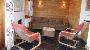 Une pièce chaleureuse avec des murs en bois, deux fauteuils à bascule, un canapé et une petite table.