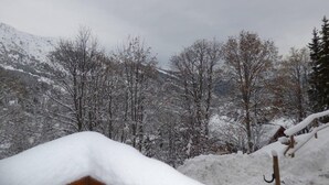 Un paysage de montagne enneigé, avec des arbres sans feuilles et une structure en bois.