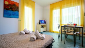 Una habitación de hotel con una cama, un escritorio con ordenador y una mesa con sillas.