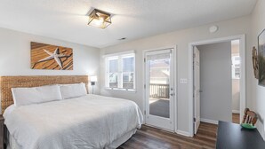 A bedroom with a bed, a ceiling light, a door, and a window.