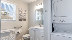 A bathroom with a toilet, sink, and a washing machine.