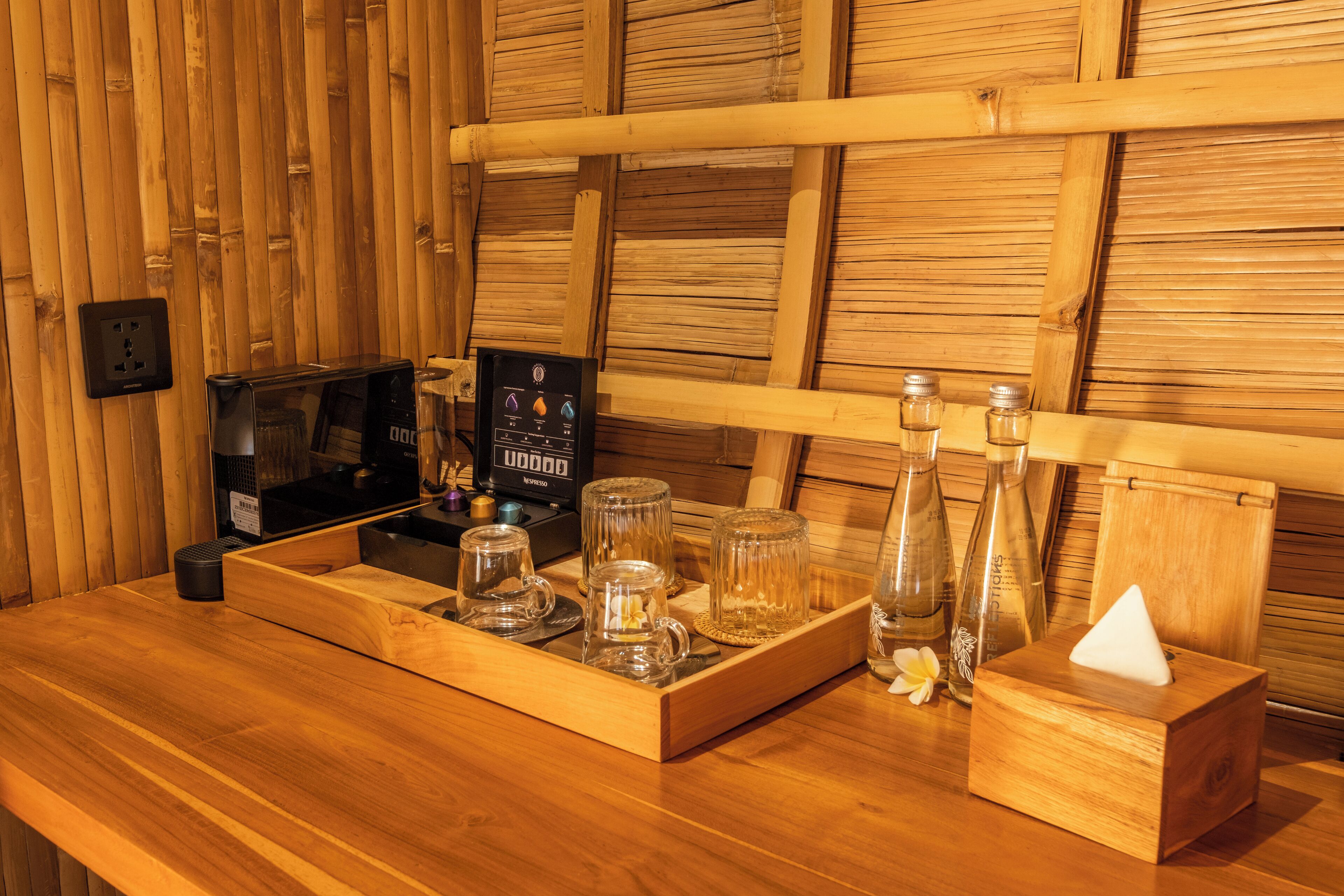 Un mostrador de recepción de madera con una pantalla digital, cristalería y una caja de pañuelos.